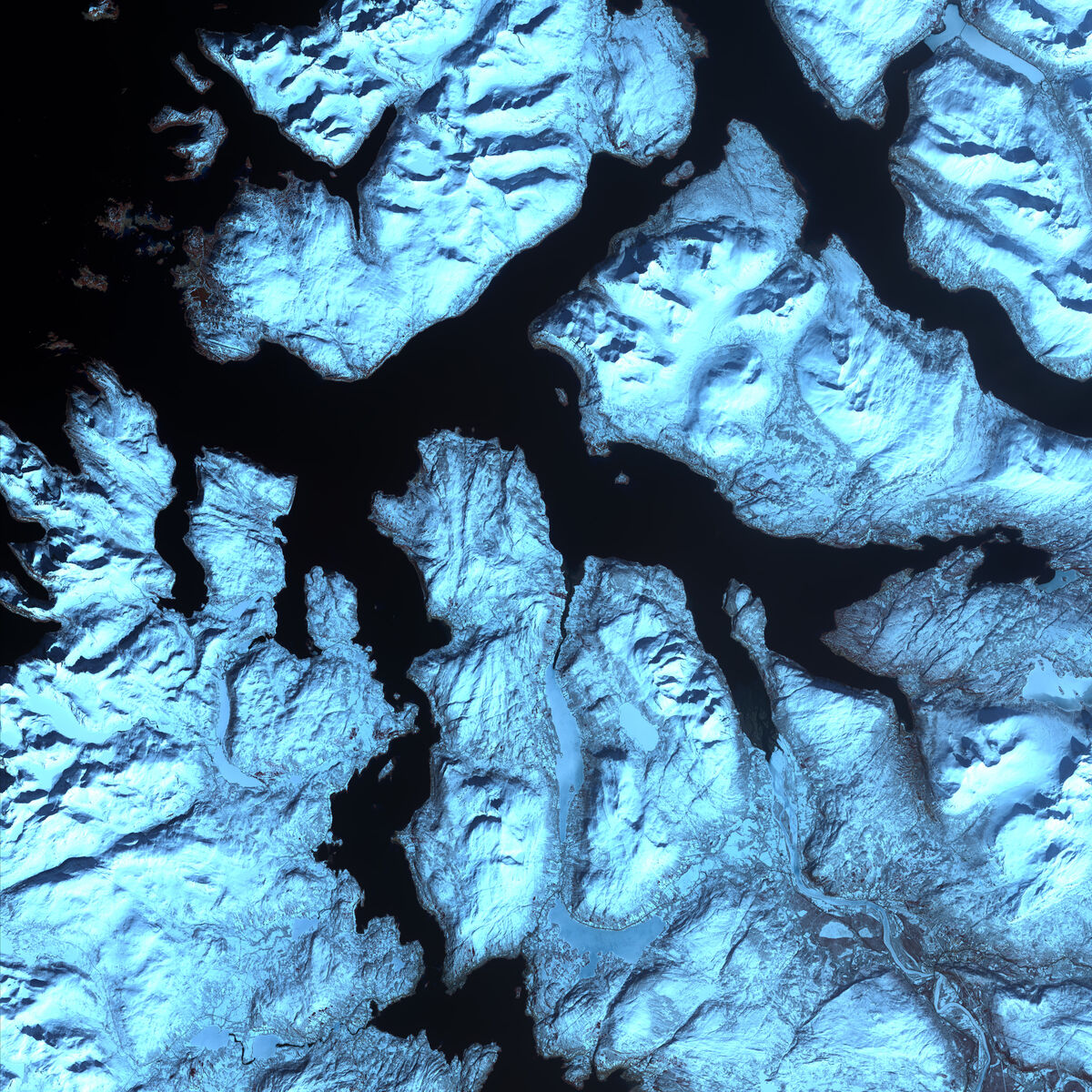 Imagem de satélite da costa recortada da Noruega: fiordes escuros e estreitos penetrando profundamente por entre montanhas cobertas de neve.